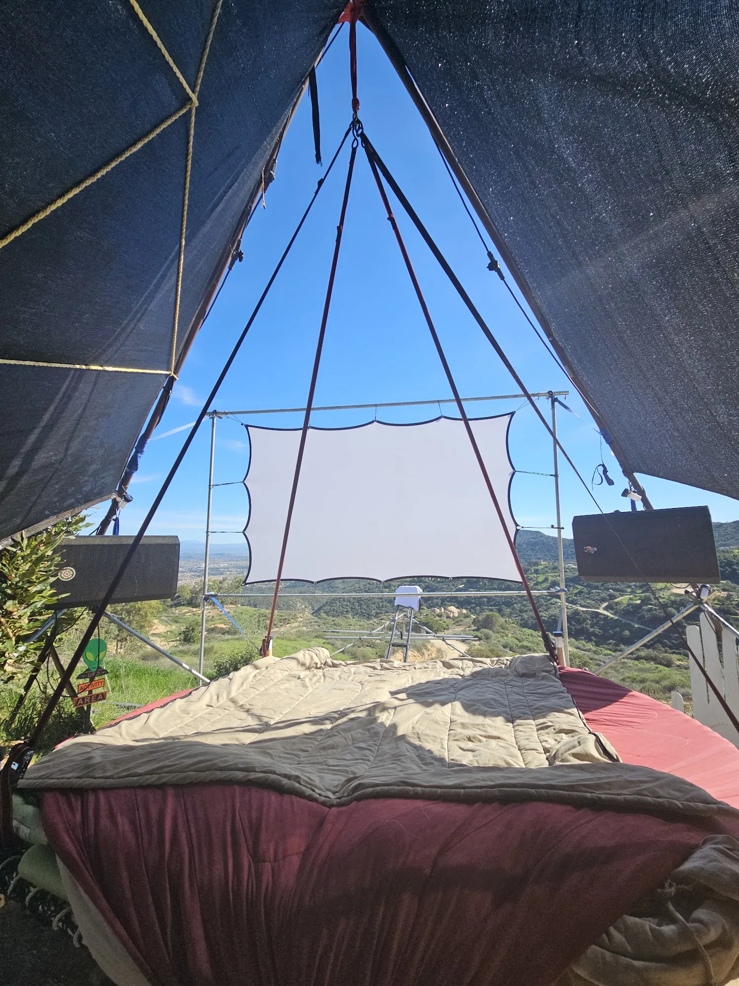 View from the bed under shade, blankets, outdoor screen, and the green valley beyond