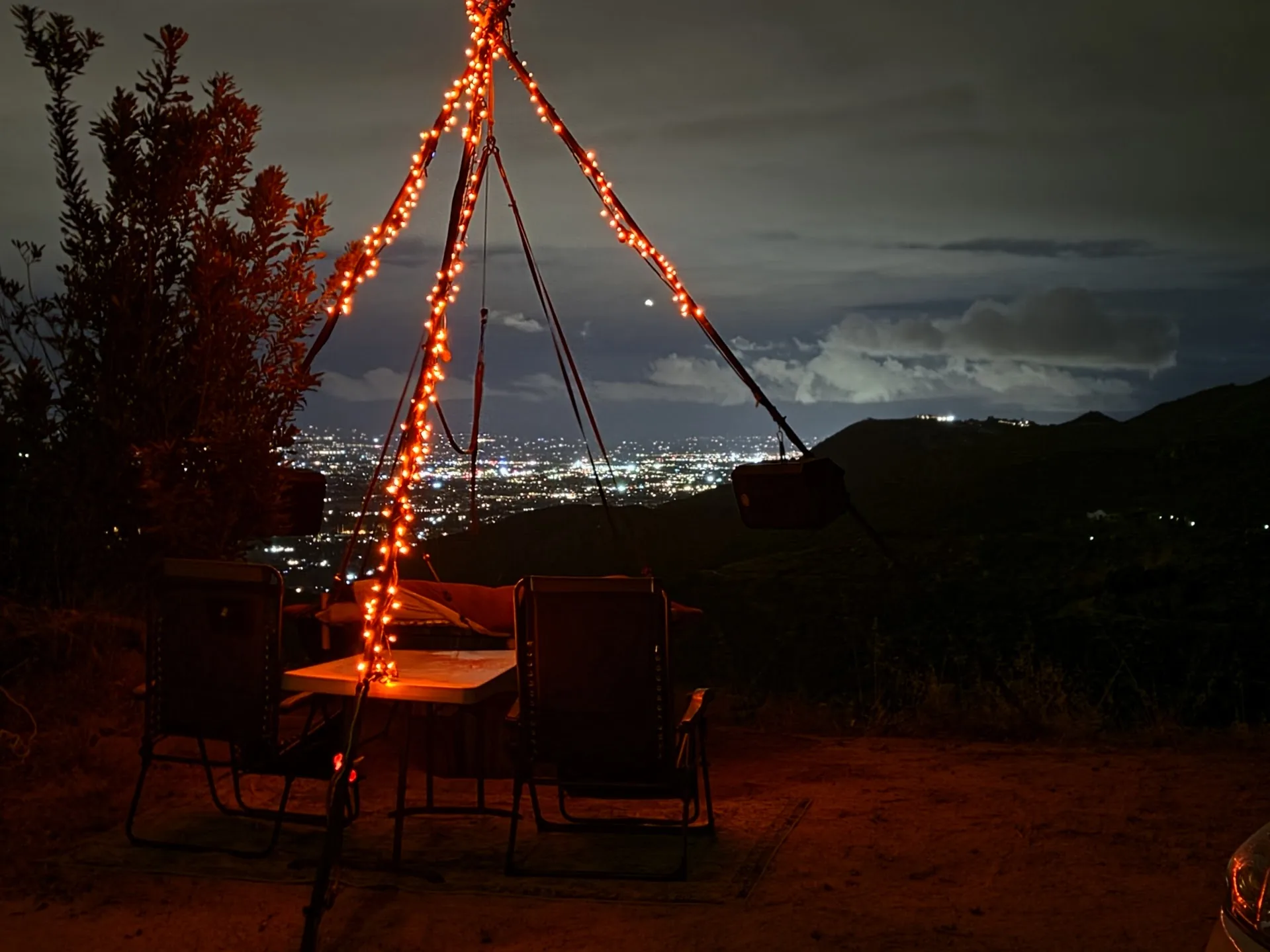 The swing at night, warm lights on the frame, the city glowing in the valley