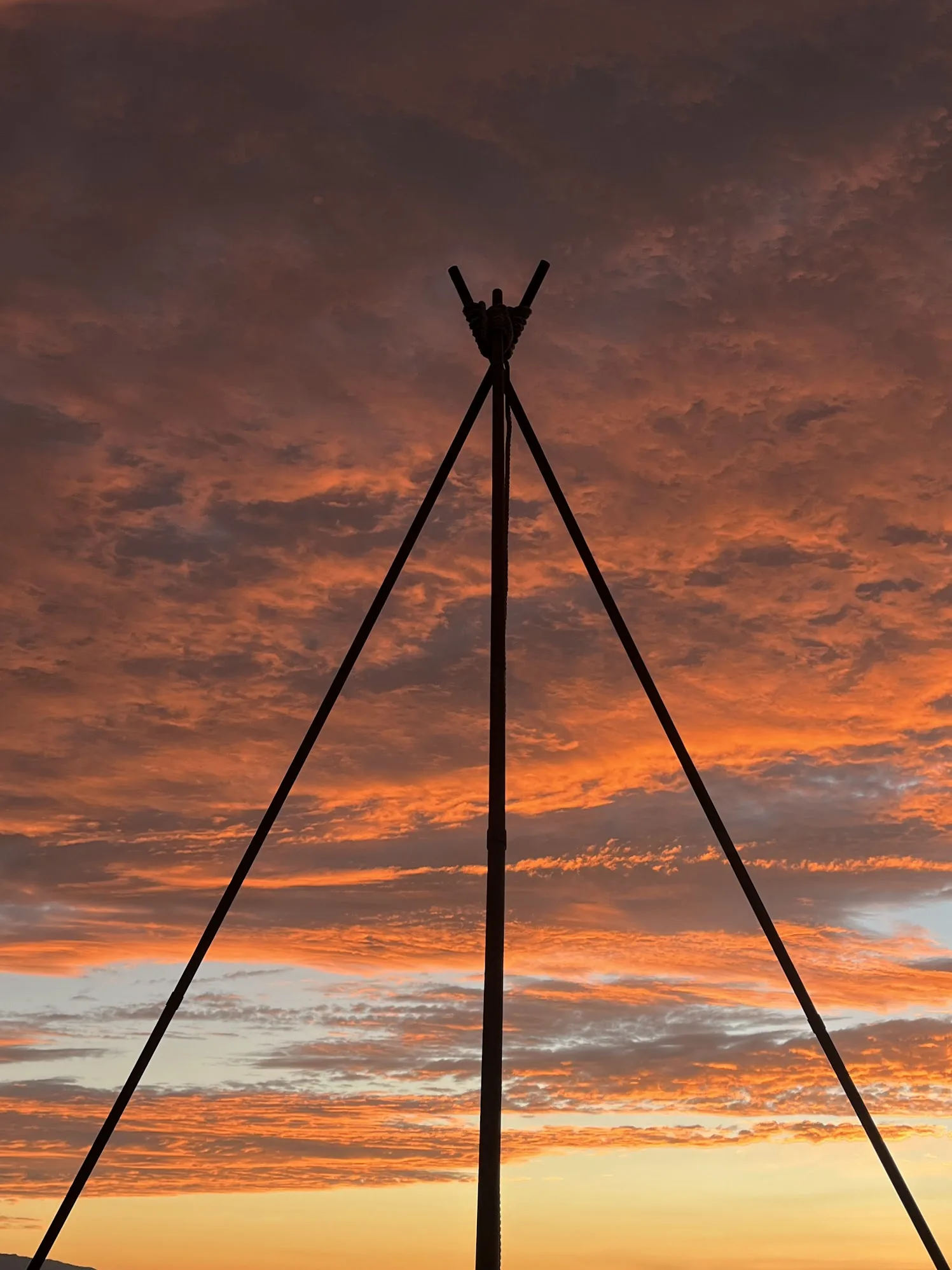The three legs of the frame meeting against a red sunset sky